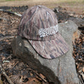 White logo camouflage dad's cap by DO IT YOURSELF HUNTER with solid camo pattern and adjustable strap.