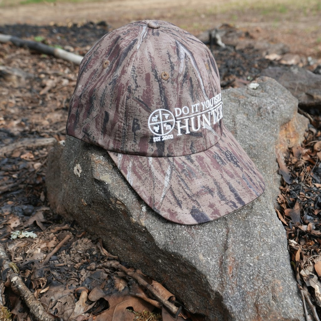 White logo camouflage dad's cap by DO IT YOURSELF HUNTER with solid camo pattern and adjustable strap.